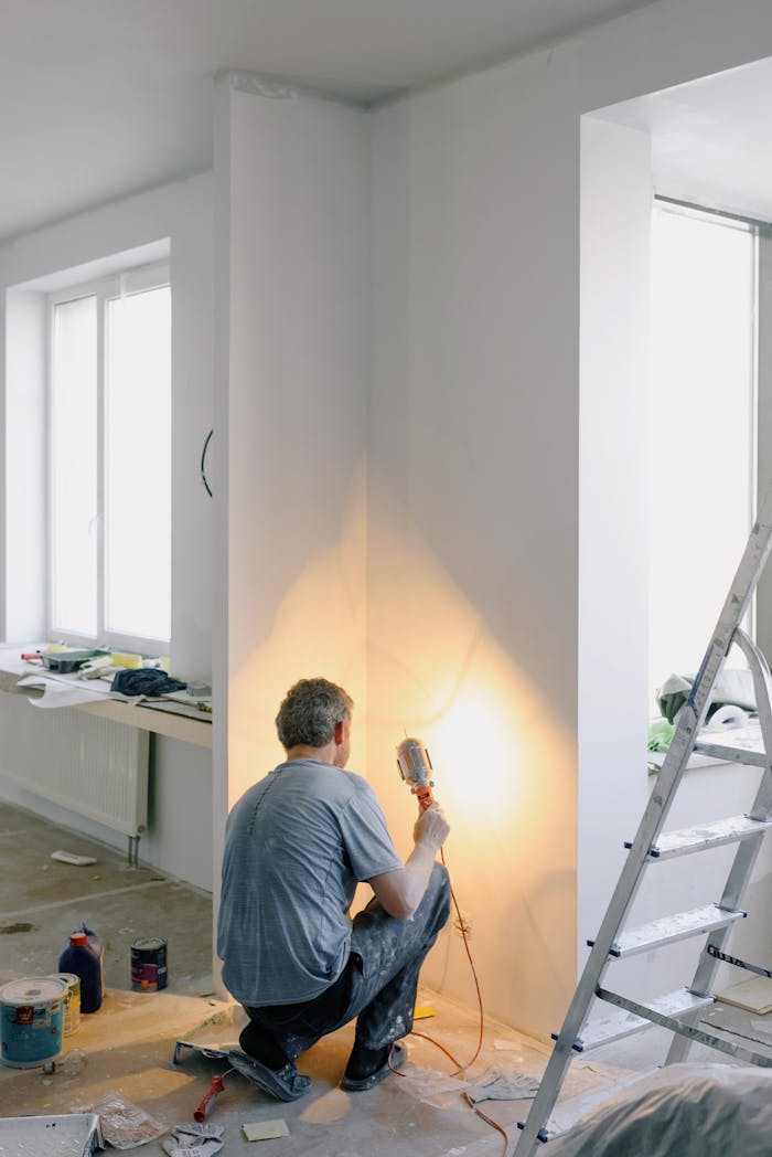 services-02 Back view of anonymous male in dirty clothes renovating walls in home while holding lamp